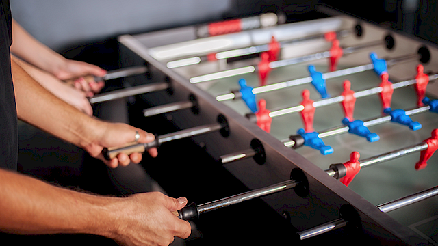 Close up shot of a game of table football being played with blue and red football players